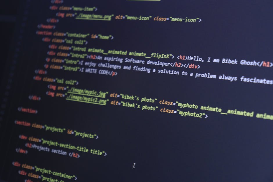 An indoor scene displaying a computer screen filled with programming code in various colours, including HTML tags and image links, set against a dark background. The code features highlighted syntax i